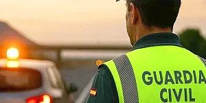 Agente de tráfico verificando la conexión de una baliza V16 en el techo de un coche.