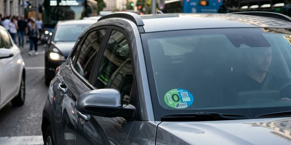 La modificación de la Ordenanza de Movilidad Sostenible de Madrid permitirá circular a los vehículos sin etiqueta empadronados en la capital mientras se cumplan los límites europeos de contaminación. Dvuelta valora positivamente el cambio, aunque reclama ayudas para renovar el parque automovilístico.